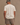 Close-up of model in Huega House Essential Tee in Cream, brushed cotton with tonal Huega logo