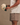 Person wearing a white t-shirt and gray shorts, holding a cap with visible branding.